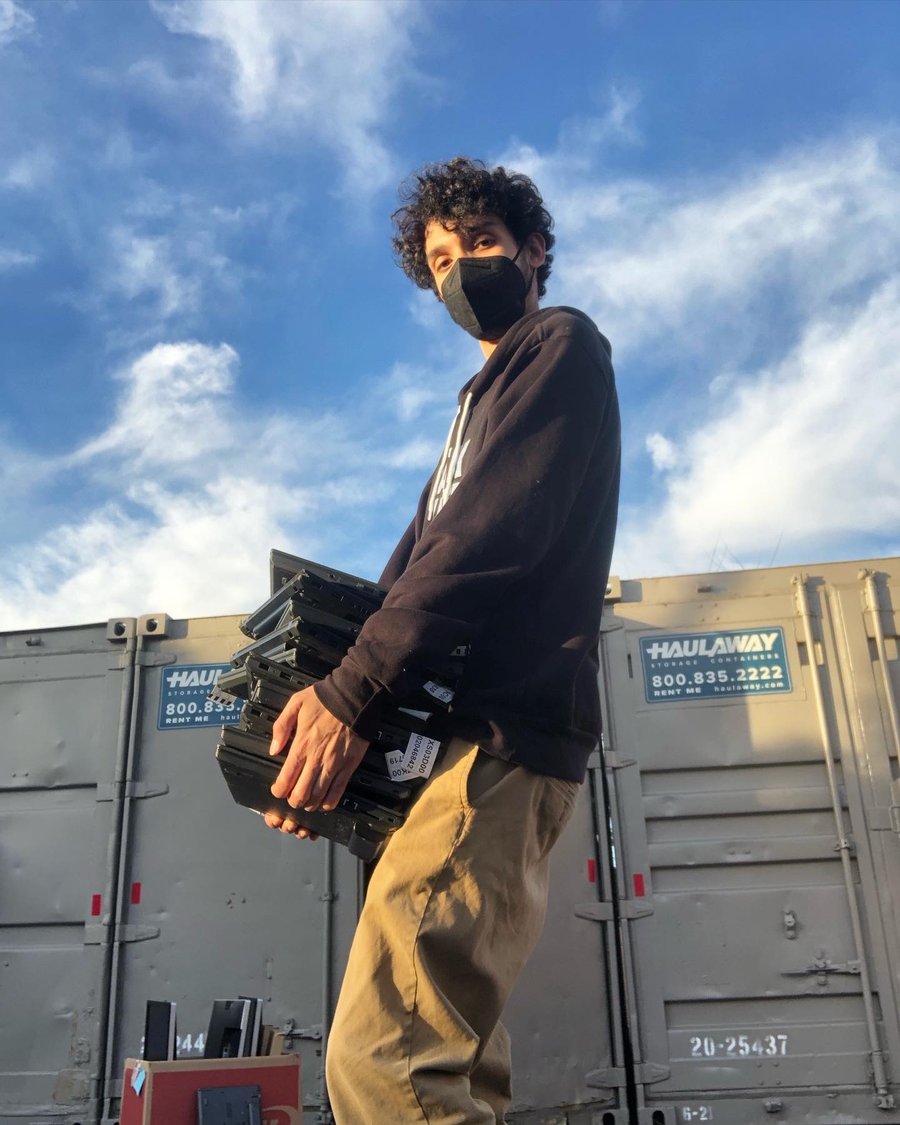 Nelson Koskela carrying salvaged laptops during e-waste work at StreetCode Academy